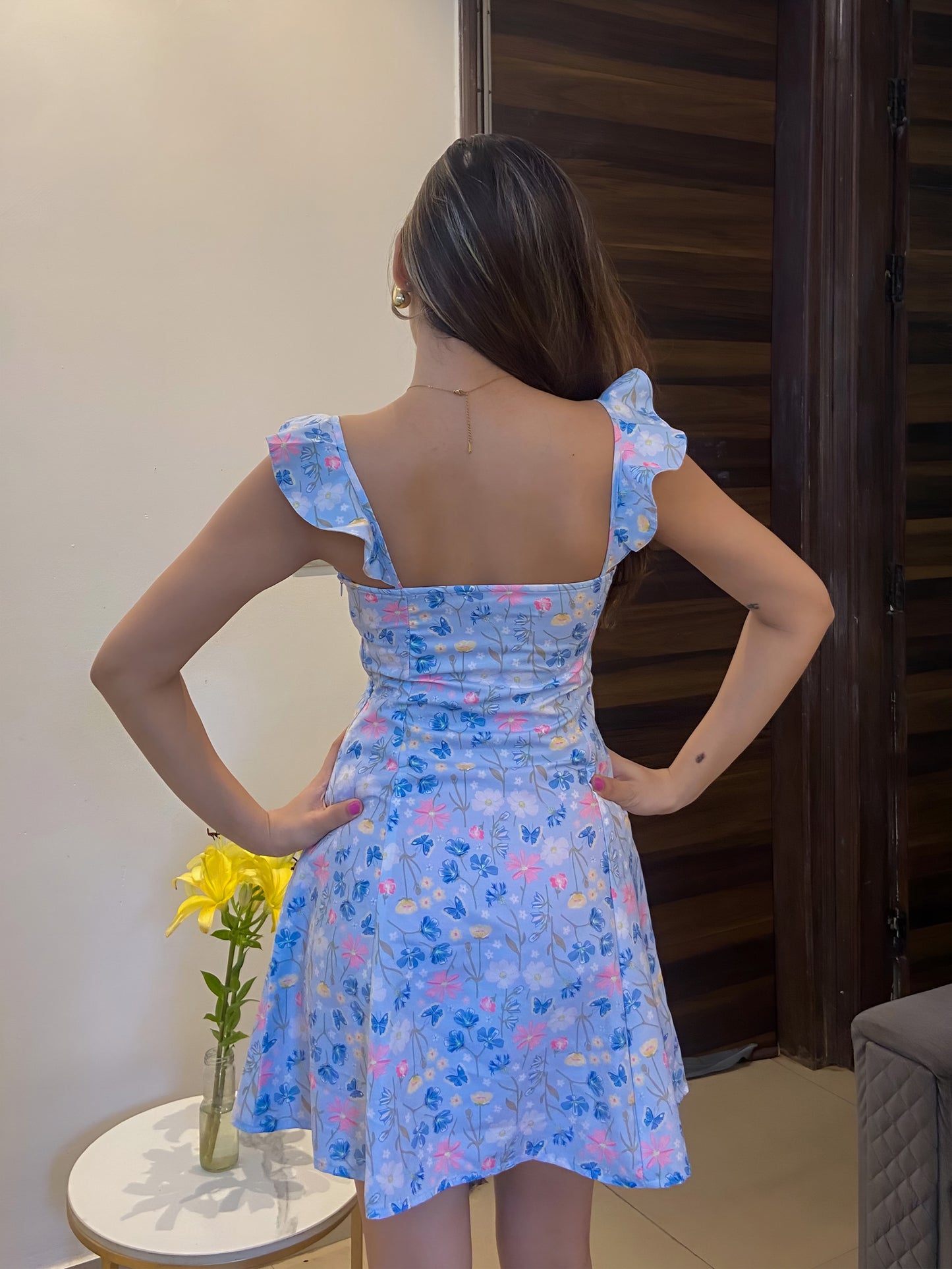 A short blue Summer floral dress, a back pose